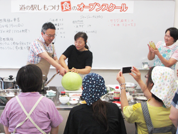 さあ調理に戻って、産地だからできるこの時季だけのお楽しみ「夕顔の実」も今日は食べちゃいましょう！臼居先生（中央右）とMC成田（左）による「夕顔の実」入刀！撮影チャンスにアシスタントの斉藤さん（右）も思わずカシャ！